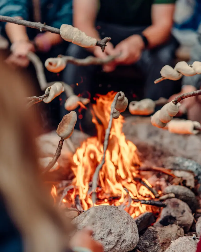 Des participants qui font cuire du pain sur une branche en bois.